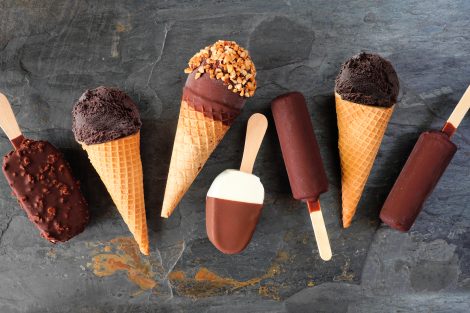 Variety of chocolate ice cream desserts. Overhead view scattered on a dark slate background.