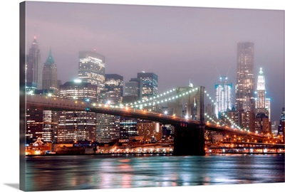 Night shot of Manhattan Skyline and Brooklyn Bridge with fog in air.