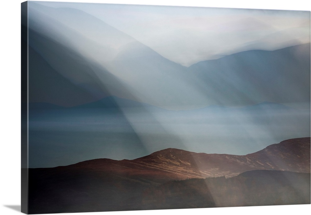 Dreamy landscape photograph of Loch Morlich in Scotland with rolling hills in the background and foreground.