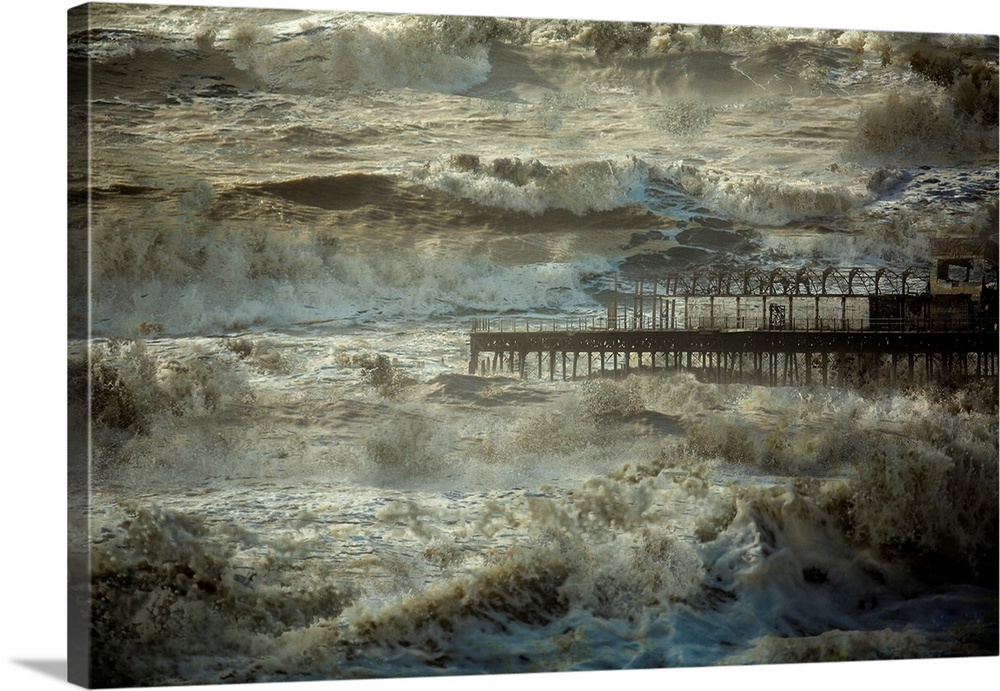 Repeated rough ocean waves crashing all around a pier.