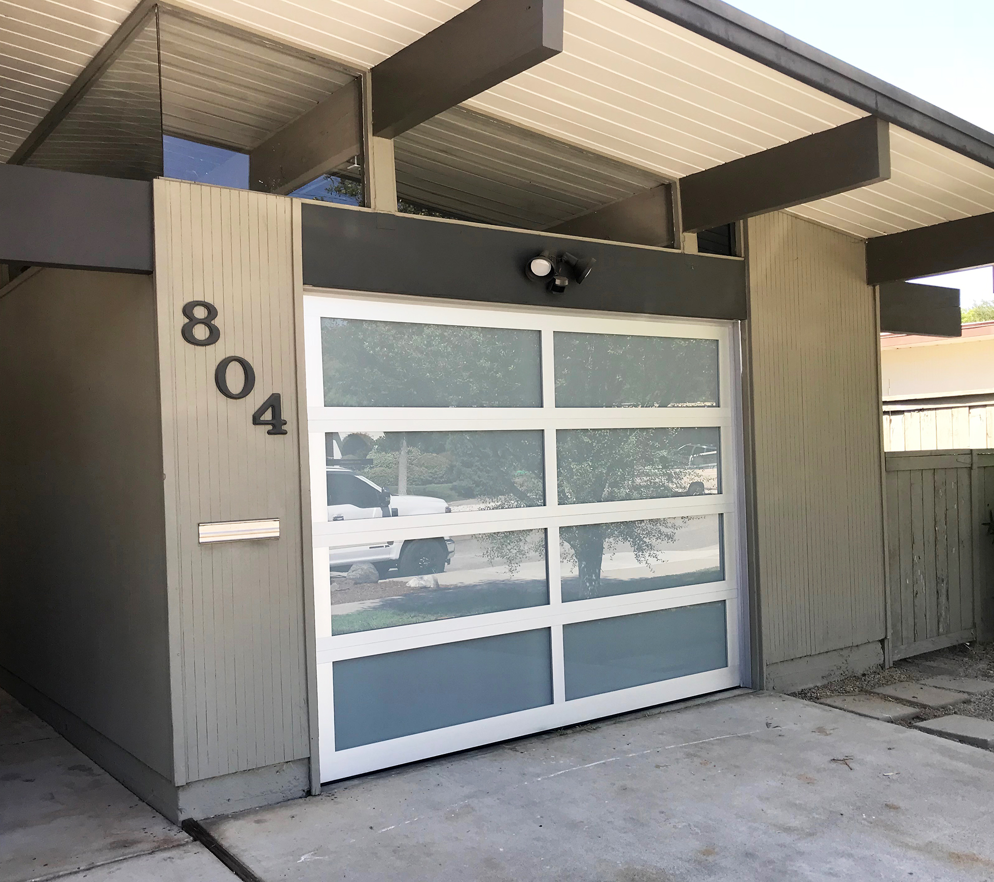 White glass garage door on gray, ranch-style home