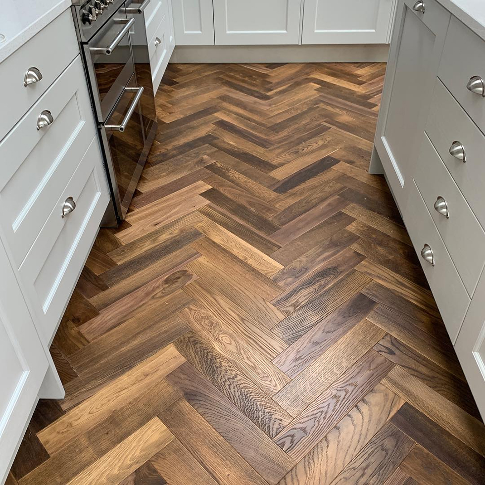 Herringbone wood floor in white kitchen with steel appliance