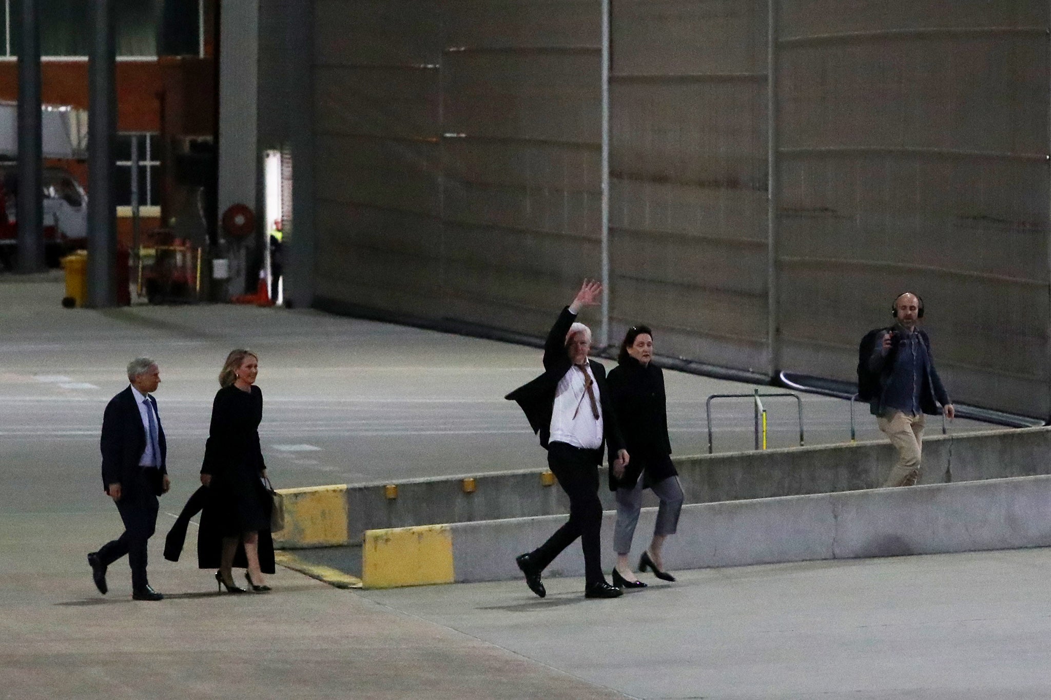 Julian Assange waves after alighting from the charter flight