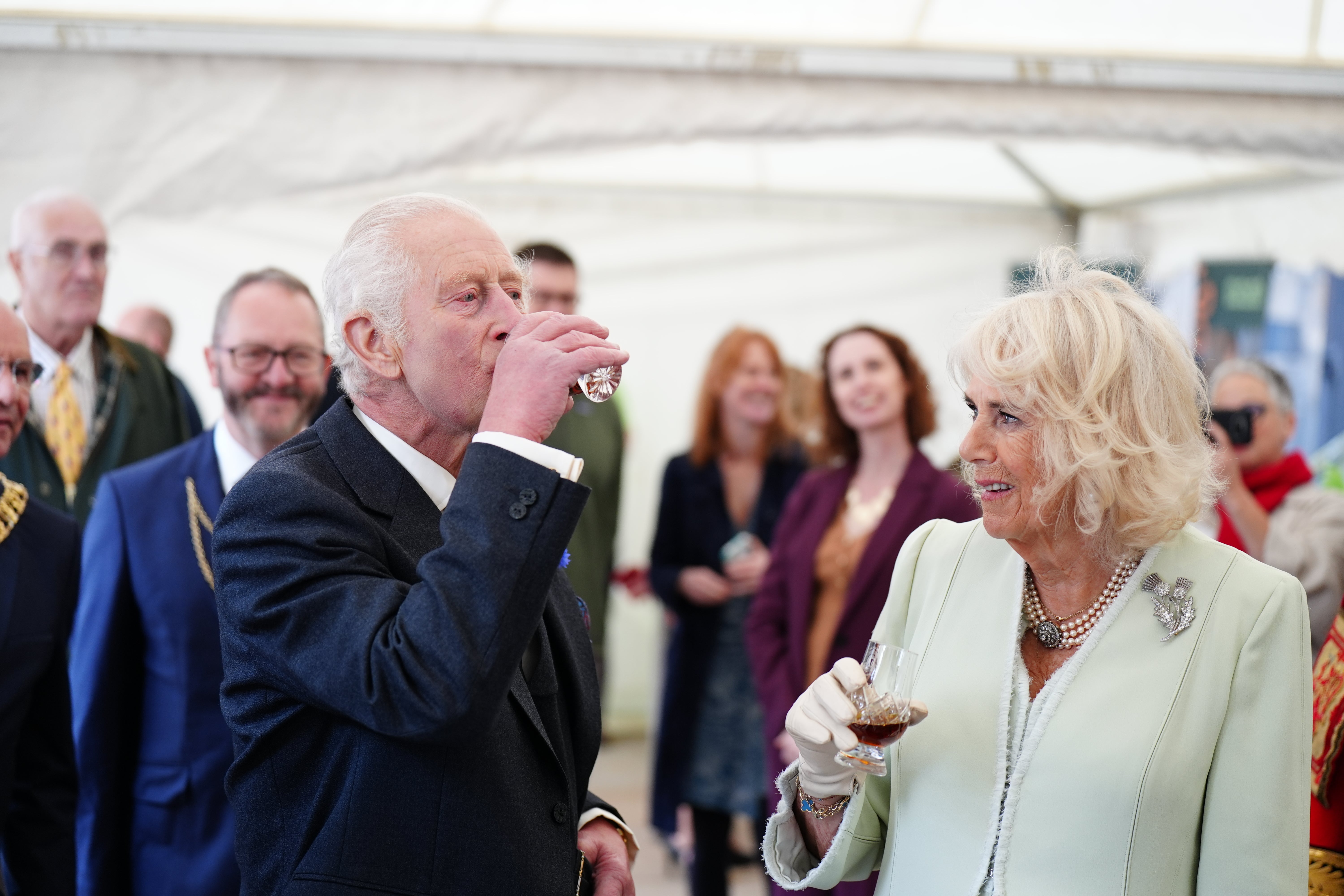 The King and Queen try a glass of whisky as they attend a celebration at Edinburgh Castle to mark the 900th Anniversary of the City of Edinburgh (Jane Barlow/PA)