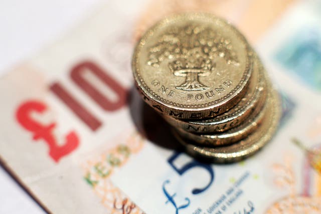 A pile of one pound coins placed on five pound and ten pound banknotes (Yui Mok/PA Wire)