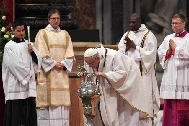 Pope Francis blows in an amphora containing holy oil during the Holy Chrism Mass on Maundy Thursday at St Peter's basilica in the Vatican on 29 March 2018