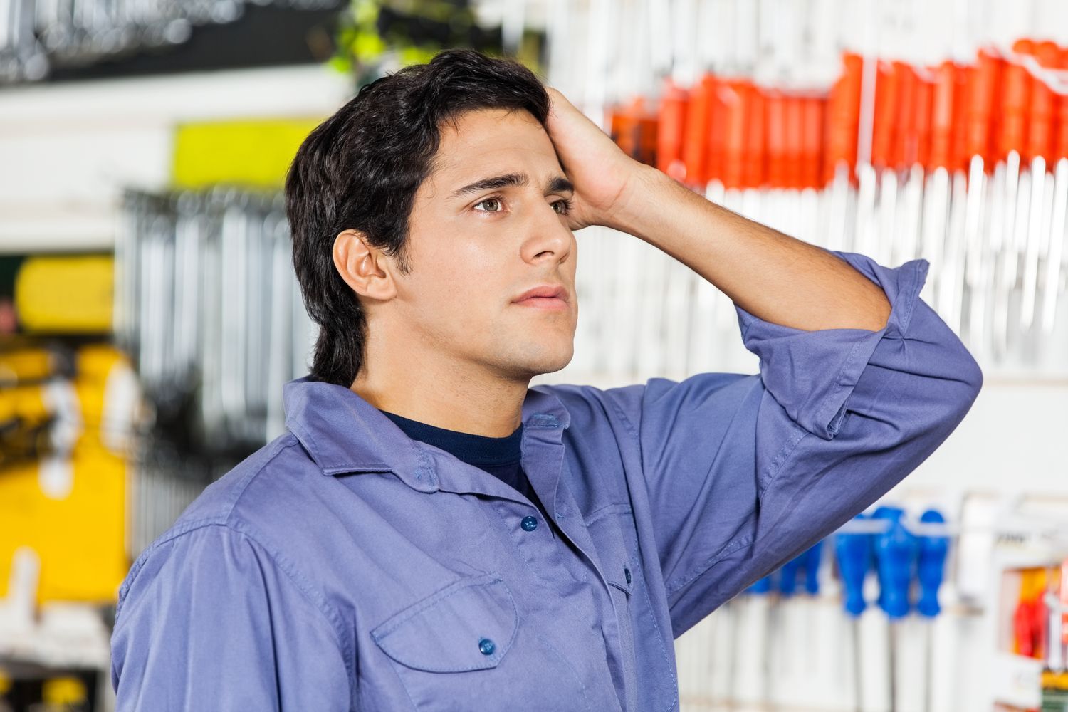 Confused male customer with hand on head looking away in hardware shop