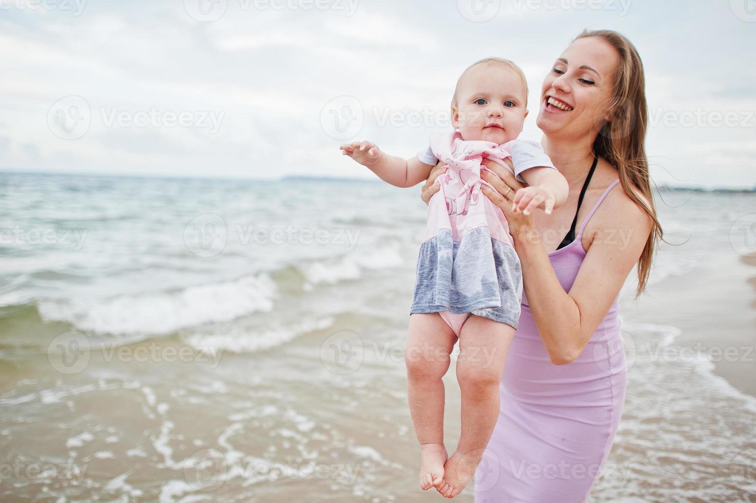 Summer vacations. Parents and people outdoor activity with children. Happy family holidays. Pregnant mother with baby daughter on sea sand beach. photo