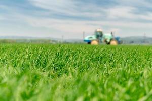 Tall field of grass with blurred tractor photo