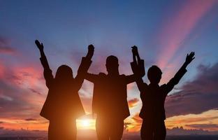 Three people silhouetted in front of sunset photo