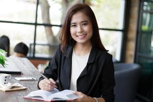 Asian businesswoman smiling holding book and pen photo