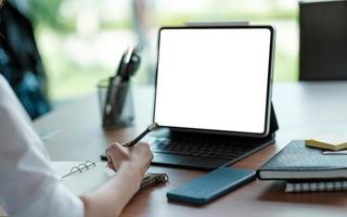 Business woman hand working at a computer and writing on a noteped photo