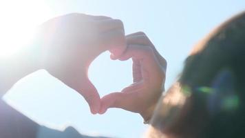 Hand of happy little girl at sunset. Happy little girl's hand reached out and made a heart shape to the sun silhouette sunlight. Heart symbol of family love. video