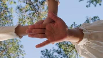 Close up of family hands put their hands together against blue sky  background on a warm sunny day. Happy people or team participation. video