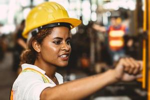 American black women teen worker working labor in industry factory with heavy steel machine. photo