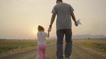 4k Video slow-motion, An Asian father took his daughter's hand for a walk. The right-hand holds a turbine During the sunset Family concept.