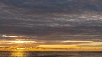 Scenic close up view of sun setting beyond the horizon over the sea. Timelapse video