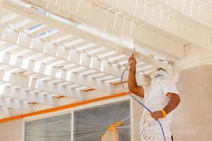 Professional House Painter Wearing Facial Protection Spray Painting Deck of A Home photo