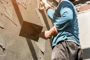 plasterer concrete worker at wall of house construction photo