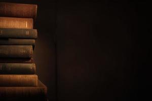 dark brown old book stack in the dark room with copy space background photo