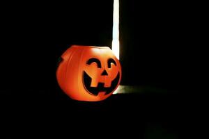 Smiling Halloween pumpkin head on black clothes in natural shadow and sunlight. Halloween holiday concept. photo