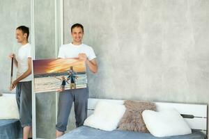 man holds photo canvas at home