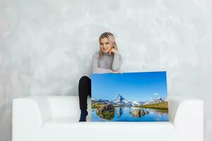 Girl hanging a frame canvas on a gray wall photo