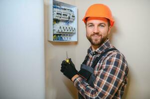 A male electrician works in a switchboard with an electrical connecting cable photo