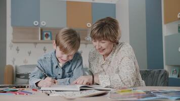 Grandma and grandson are doing homework. Portrait of a happy family. Learning at home. Teaching. Grandmother and grandson laugh. Cute emotions in the frame. The story of one family. video