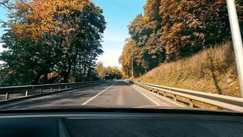 View through the windshield of the car to the road. A trip by car driving along an asphalt road through an autumn forest video