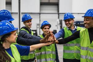 Team of multiracial engineers stacking hands together inside robotic factory - Tech industry concept photo