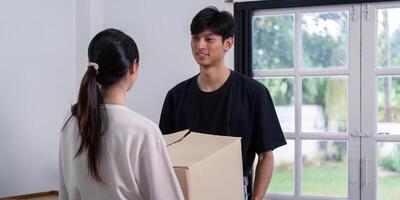 Young Couple Moving into New House, Carrying Boxes and Smiling in Bright Modern Home with Large Windows photo