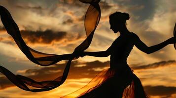 A silhouette of a ribbon dancer against a sunset sky their fluid movements creating a captivating spectacle photo