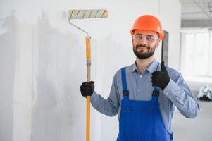 Portrait of young and hardworking constructor posing in big unfinished room. Building concept photo