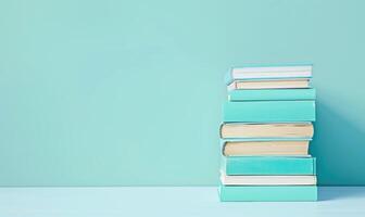 Stack of books on a white table with a pastel blue background photo