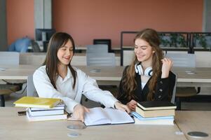 Two schoolgirl friends study together. They sit at their desks and perform tasks. photo