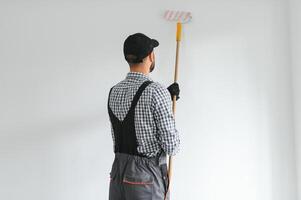 Young worker painting wall in room. photo