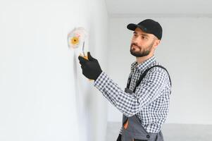 Young worker painting wall in room. photo