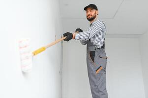 Young worker painting wall in room. photo