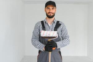 Young professional worker in uniform standing with paint roller. photo