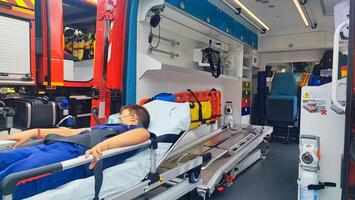 A teenage boy lies on a gurney in an ambulance, to provide first aid. Saving the life of a small ambulance patient. photo