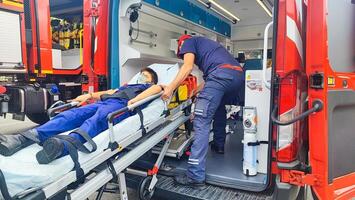 A teenage boy lies on a gurney in an ambulance, a rescue worker helps him and provides first aid. Saving the life of a small patient by an ambulance doctor. photo