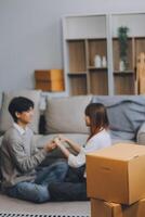 Asian Female discussing new project with male colleague. Young woman talking with young Asian man with financial on sofa in home office photo