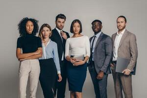 Confident young business team looking at camera while standing on beige background together photo