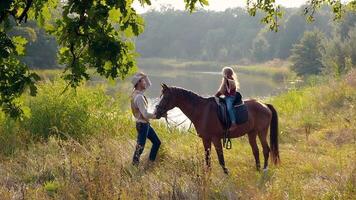 Cowboy and his daughter on horseback on the river bank. Happy cowboy family. Slow motion. video