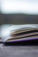 Open book with pages flipping in the wind. Reading on the lake wooden dock on autumn day. Learning enjoying tranquility of nature. Peaceful outdoor environment. Selective focus. Blurred background. photo