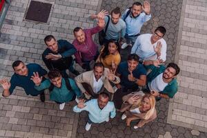 A top view photo of group of businessmen and colleagues standing together, looking towards the camera, symbolizing unity and teamwork.