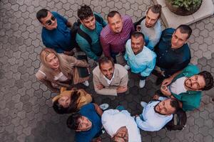 A top view photo of group of businessmen and colleagues standing together, looking towards the camera, symbolizing unity and teamwork.