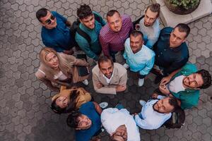 A top view photo of group of businessmen and colleagues standing together, looking towards the camera, symbolizing unity and teamwork.