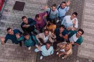 A top view photo of group of businessmen and colleagues standing together, looking towards the camera, symbolizing unity and teamwork.